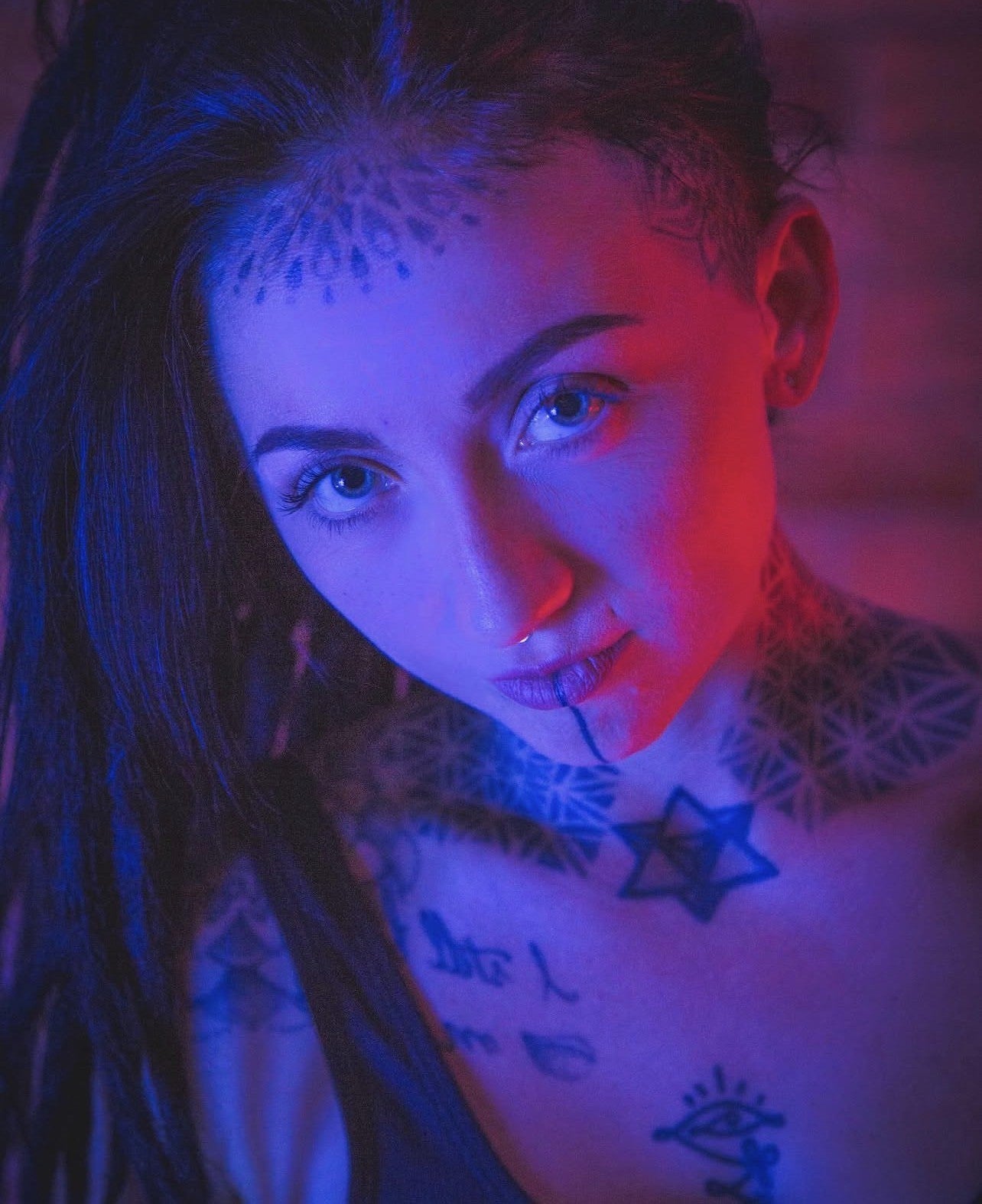 Person with tattoos in a neon-lit setting